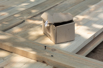 A box of screws on a wooden surface, a formwork for a fence