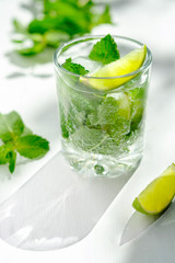 Cold refreshing summer Mojito lemonade in a glass on a white background. Lime, mint, ice.
