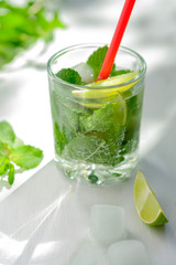 Cold refreshing summer Mojito lemonade in a glass on a white background. Lime, mint, ice.