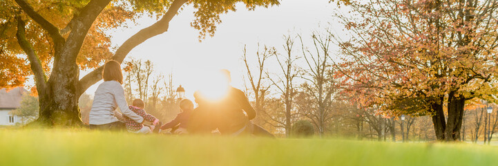 Panorama rear view of young family with three kids enjoying a day together