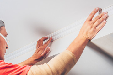 finishing works - the worker decorates the ceiling with stucco molding