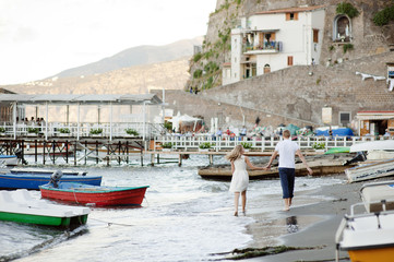 Fototapeta na wymiar A young couple walks along the beach, in the port of Sorrento.