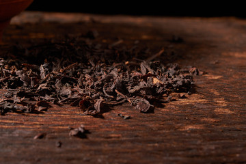 Dried black tea in wooden bowl isolated on white background with clipping path