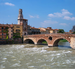 Fototapeta premium Ancient Roman bridge Ponte Pietra and the River Adige in cloudy summer day, Duomo tower in background, Verona, Italy