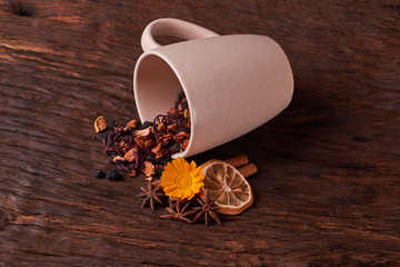 cream cup and leaves of tea, fruits and dried fruit tea on rustic wooden table background. Selective focus