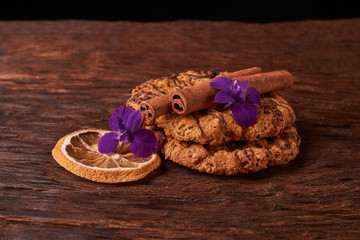watered chocolate syrup cookies on wooden table. Cute composition with flowers and sticks of cinnamon. Selective focus