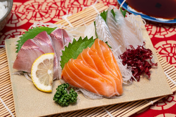 sashimi set on a plate with rice and soy sauce and chopsticks