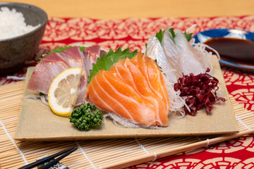 sashimi set on a plate with rice and soy sauce and chopsticks