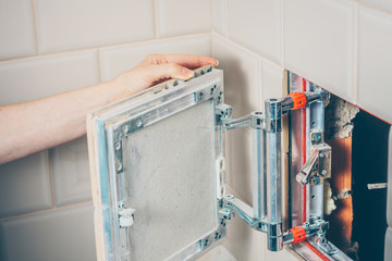 The girl opens a hidden hatch on the wall of the tile to access the inspection hole of the sewer...