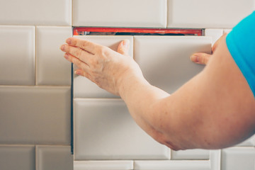 The girl opens a hidden hatch on the wall of the tile to access the inspection hole of the sewer...