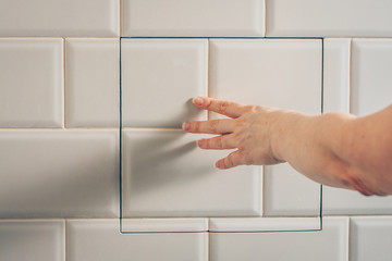 The girl opens a hidden hatch on the wall of the tile to access the inspection hole of the sewer pipe to eliminate clogging and cleaning