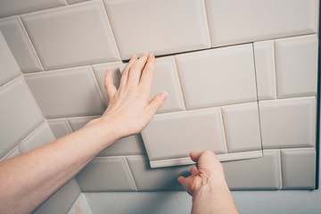 The girl closes the sanitary hatch on the wall of the tile and closes the access to the plumbing and sewer systems at hom.