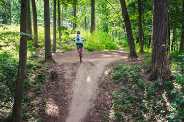 A cyclist in a helmet descends from the mountain on an orange bicycle