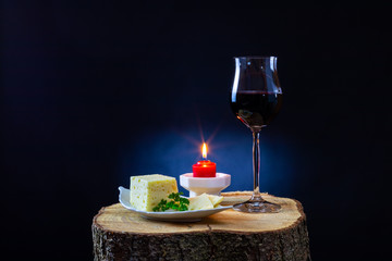 Rotwein serviert mit Käse und Kerze auf einem Baumstamm