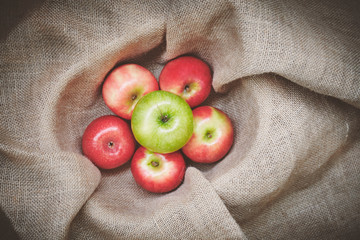 Top view red apples, green apples in basket cover with brown cloth background texture