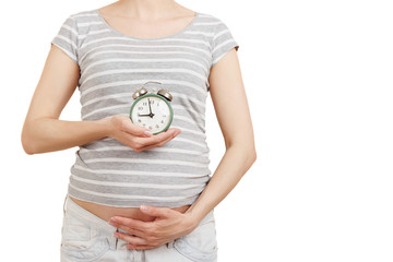 Pregnant woman with an alarm clock in the hands