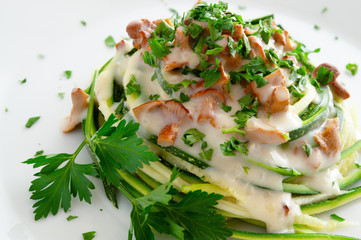 zucchini spaghetti under white sauce with chanterellas decorated with parsley leafs