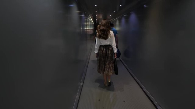 Passanger woman go out of airplane, walk in aerobridge