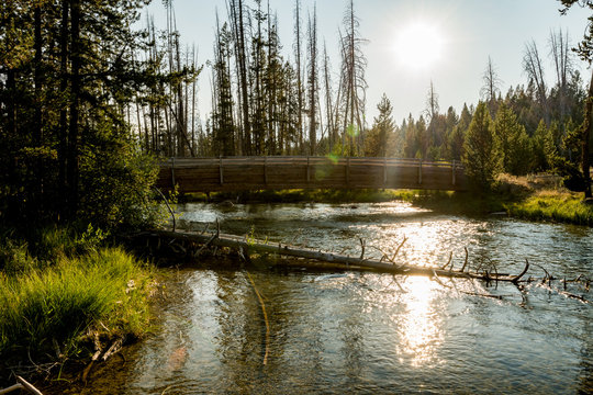 Sun sets down behind a fancy wood bridge on a river leading from Redfish Lake Idaho