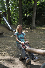 eine frau lächelt in einem park von einer wippe auf dem kinderspielplatz