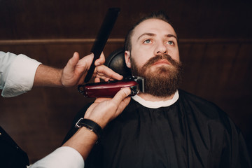 Barbershop with wooden interior. Bearded model man and barber.