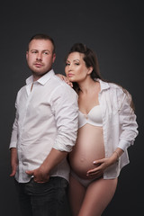 Young pregnant woman with husband on dark background