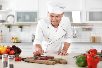 Professional chef cooking meat on table in kitchen