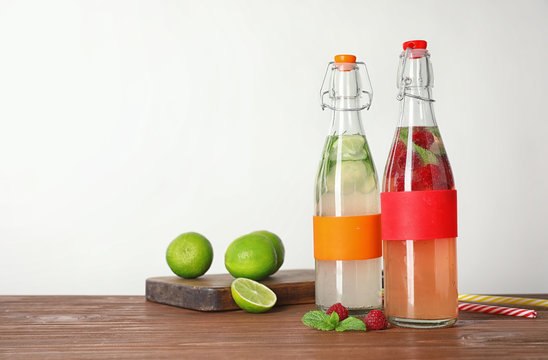 Bottles with natural lemonade on table against white background
