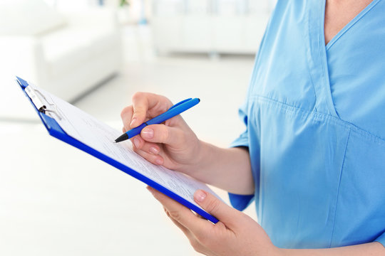 Female medical assistant with clipboard in clinic, closeup. Health care service