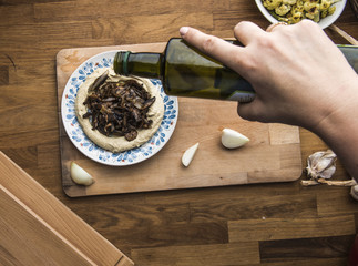 pouring olive oil on a plate of mushroom hummus
