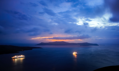 Cruise ships are resting in harbour at Santorini, Greece, after the sunset, in the blue light of the sky.