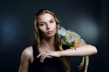 perfect portrait beautiful girl and green iguana in the studio
