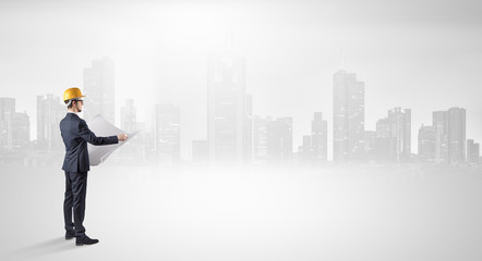 Young supervisor architect standing and looking at a big city panorama
