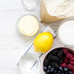 Raw ingredients: berries, lemon, flour, sugar, salt, water for cooking berry pie, overhead view. From above, top view, flat lay. Close-up.