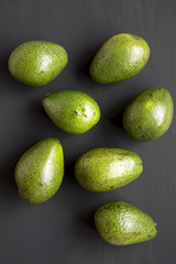 Whole avocados on dark wooden background, top view. Overhead, from above.