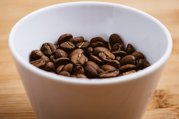 Cup of Coffee Beans roasted on a wooden table with fresh bean with great aroma