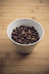 Cup of Coffee Beans roasted on a wooden table with fresh bean with great aroma