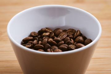 Cup of Coffee Beans roasted on a wooden table with fresh bean with great aroma