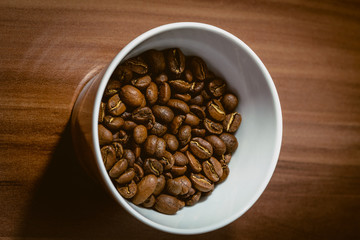 Cup of Coffee Beans roasted on a wooden table with fresh bean with great aroma