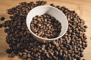 Cup of Coffee Beans roasted on a wooden table with fresh bean with great aroma