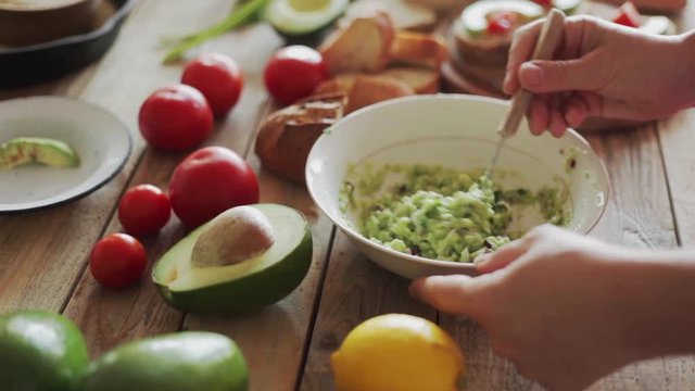 Mexican cuisine - making guacamole, avocado crushed using kitchen fork, close-up, steadicam