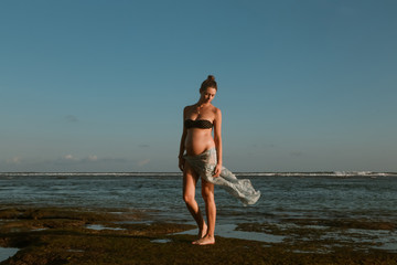 Fototapeta na wymiar Young pregnant woman on the beach, vacation during pregnancy time