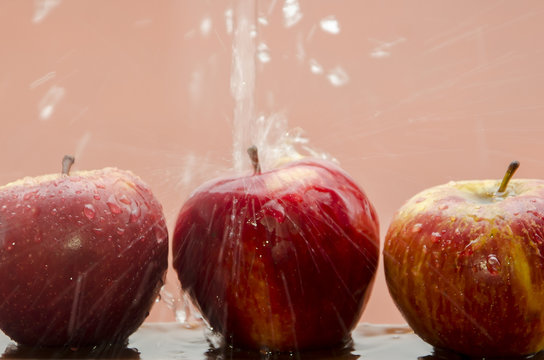 Tres manzanas moj&aacute;ndose sobre fondo rojo