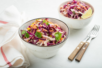 Purple cabbage and carrot salad with mayonnaise in a white bowl on a light background. Classic coleslaw. Diet vegetarian dish