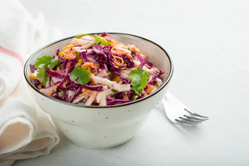 Purple cabbage and carrot salad with mayonnaise in a white bowl on a light background. Classic coleslaw. Diet vegetarian dish. Copy space