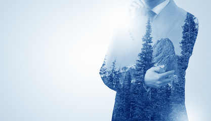 Young businessman standing and meditate with trees on the background 