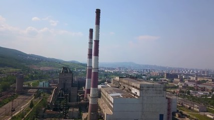 Aerial drone footage of the factory with the city on the background
