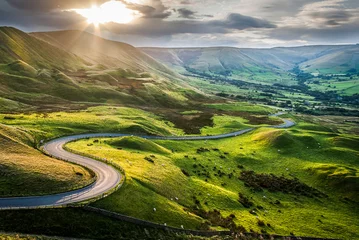 Fotobehang Sunset at Mam Tor, Peak District National Park, with a view along the winding road among the green hills down to Hope Valley, in Derbyshire, England. © Adrian