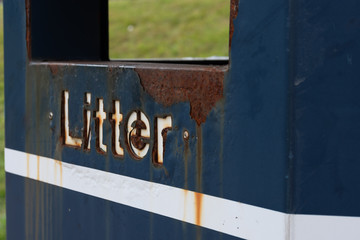 Rusted litter sign on blue bin