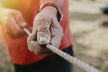 older man's hands pulling the rope